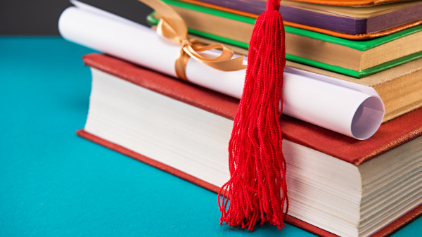 close up of books diploma and graduation cap