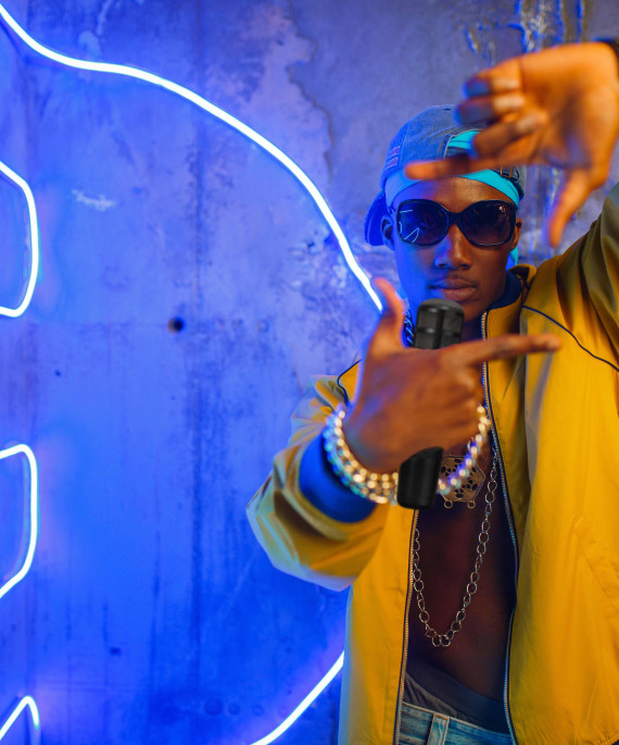 Rapper standing next to neon lights with a microphone
